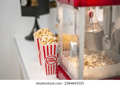 Home theatre popcorn maker with popcorn containers red and white striped, full of butter popcorn in vintage popcorn maker - Powered by Shutterstock