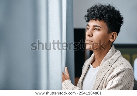 Home, thinking and man by window with social anxiety, reflection or winter burnout. Depression, mental health and tired person in bedroom for emotional stress, decision or planning in apartment