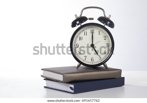 Home Time Concept With An Old Fashioned Alarm Clock With Bells And The Time Set To Five On Top Of School Books Or Office Journals With Copy Space