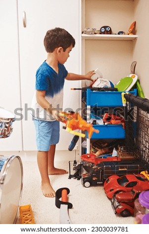 Home, toys and boy playing, relax and learning with development, happiness and organized. Male child, kid or young person with games, playful and growth in a room, cleaning or creativity in a bedroom