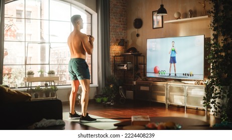 Home Training: Handsome Muscular Black Man Using Kettlebell, Exercising With Trainer Via TV Online Video App. Strong Mixed Race Sportsman Using Workout Service Fitness Streaming App For Virtual Gym.