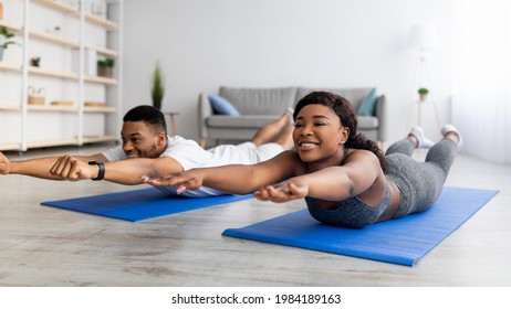 Home trainings during covid lockdown. Strong black couple exercising on sports mats, doing yoga or pilates indoors, panorama. Athletic African American family leading active lifestyle