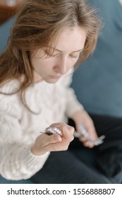 Home Treatment - A Young Woman Parses Packages Of Medicines And Pills Purchased With A Doctor S Prescription. Pharmaceuticals, Painkillers And Antibiotics In The Hands Of A Girl Sitting On The Bed