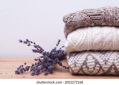 Home Wardrobe With Winter Clothes. Woolen Sweaters And Dried Lavender For Protection From Moth. Knitted Warm Wool Clothes. Stack Of Warm Knitted Clothes With Lavender. Autumn, Winter Season Knitwear.