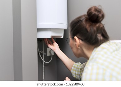 Home Water Heater, A Woman Regulates The Temperature On An Electric Water Heater, Comfort And Hot Water In The House