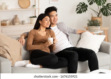 Home Weekend. Lovely Filipino Couple Watching Film Resting On A Couch At Home, Copy Space