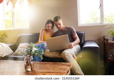 Home Is Where The Hotspot Is. Shot Of A Happy Young Couple Using A Laptop Together On The Sofa At Home.