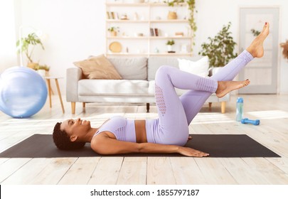 Home workout during covid-19 lockdown. Fit black woman doing air cycling exercise on yoga mat at home. Athletic African American lady training her abs muscles, having strength workout indoors - Powered by Shutterstock