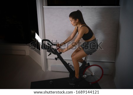 Home workout indoor stationary bike Asian girl biking screen with online classes woman training on smart fitness equipment indoors for cycling exercise. Late at night in bedroom. Stock photo © 