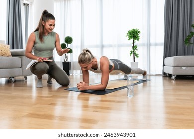 Home workout with personal trainer. Two young women physiotherapist and client training for stability, body and mental health. Businesswoman paying professional coach to help her. - Powered by Shutterstock