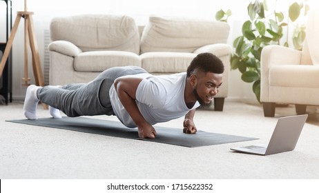 Home Workout. Sporty Young Black Man Making Fist Plank Exercise In Front Of Laptop, Watching Fitness Tutorials Online, Panorama