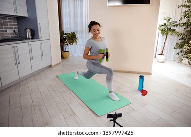 Home workout training of a fitness woman doing lunges exercises for leg muscle while watching tutorials.