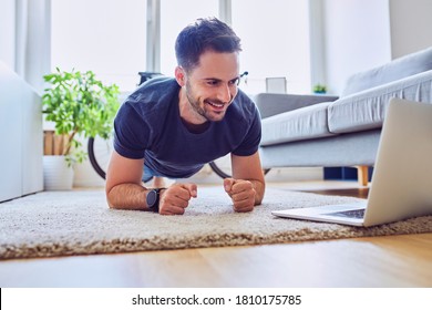 Home Workout. Young Man Doing Plank Exercise While Watching Online Class On Laptop.