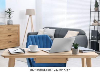 Home workspace. Laptop, cup of coffee and stationery on wooden desk indoors - Powered by Shutterstock