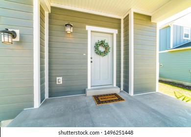 Home With Wreath On The Front Door And Green Horizontal Siding On The Wall