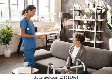 Homecare of elderly generation. Medical worker nurse caregiver visiting old disabled handicapped lady at home hospice, private clinic for elderly people. Geriatrics - Shutterstock ID 2395115069