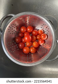 Homegrown cherry tomatoes in a stainless steel colander