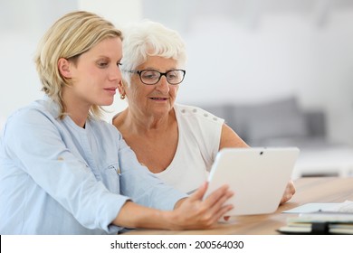Homehelp with elderly woman using digital tablet
