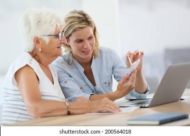 Homehelp with elderly woman using smartphone