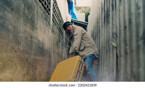 A Homeless Asian Man Is Dragging A Large Suitcase In A Narrow Alley. To Find Jobs And Food From People Who Will Donate An Elderly Man With No Work, No Home, And On The Roadside.