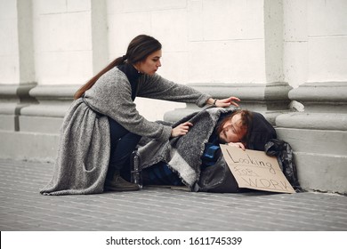 Homeless In A City. Man Asking For Food. Man With A Tablet. Girl Helping A Homeless