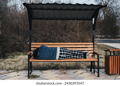homeless elderly old man lies sleeping on a park bench in autumn
