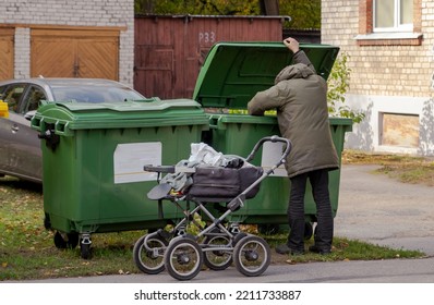 Homeless Guy Looking For Food In Green Garbage Cans On The Street. Life On The Street. Lifestyle Of A Tramp, Living In The Streets