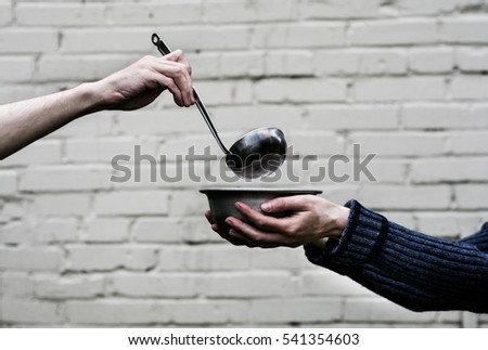 Homeless. In the hands of one man metal plate. In the hand of another person ladle.
