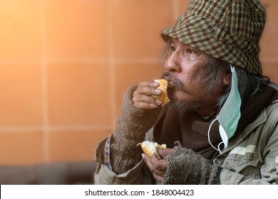 Homeless and hungry. Close up of senior man eating bread.
