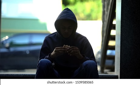 Homeless Hungry Guy Eating Sandwich Sitting In Darkness On Stairs, Crisis