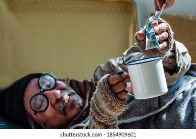 A Homeless, Impacted By The Coronavirus Man Asks For Money Or Food Help From Passers-by On The Street Side With A Help Sign.