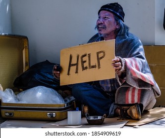 A Homeless, Impacted By The Coronavirus Man Asks For Money Or Food Help From Passers-by On The Street Side With A Help Sign.