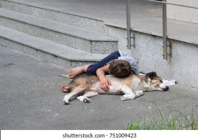 Homeless Kid Sleeping With His Dog On The Streets In Bucharest, Romania, East Europe - 9 July 2014- Concept Of Poverty, Social Differences, Cruelty. Human Best Friend.