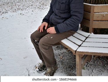 homeless man, abandoned lonely and frail. When spending the night in a park on a snowy circle shape bench, it can get cold or cause frostbite.