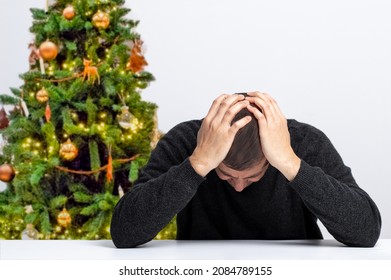 Homeless man addicted to drugs and alcohol sitting alone and depressed feeling anxious and alone at home, with a christmas tree