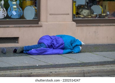 A Homeless Man Lies On The Bare Ground With Only A Sleeping Bag