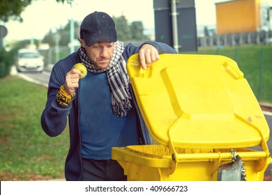 A Homeless Man Looking For Food In A Garbage Dumpster. 