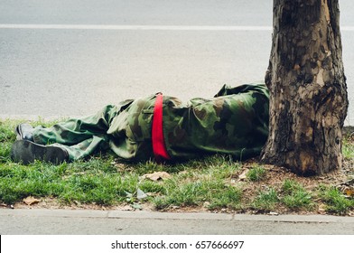 Homeless man in military uniform sleeps on the street. 