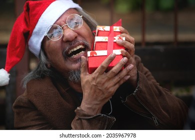 Homeless man in a Santa hat closes his eyes and happily hugs his Christmas present