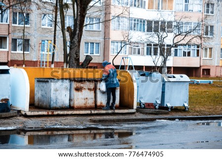 Homeless man is searching the trash in a trash bin on street