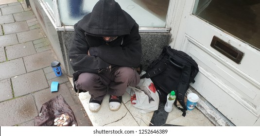 Homeless man sitting in doorway at christmas begging for money in the rain.