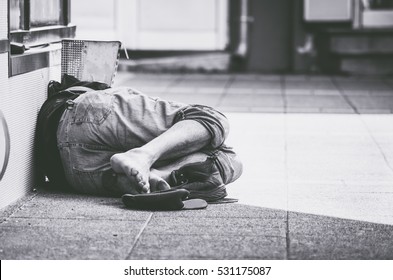 Homeless man sleep on the street in the shadow of the building. 
