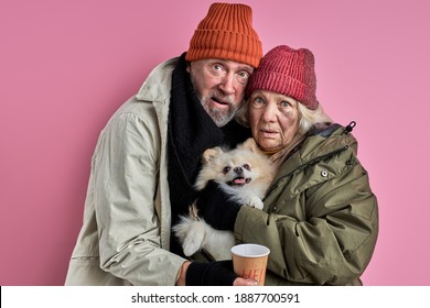 homeless man and woman with dog in hands need help, stand scared of something, isolated on pink background - Shutterstock ID 1887700591