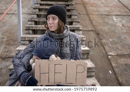 homeless mother with child with a sign Help on the stairs in abandoned place No war A homeless child with dirty face and hands needs help. Social problems, Homelessness, refugee problems, fleeing war