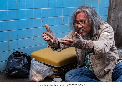 Homeless Old Man Reaching Out To Passerby Ask For Money, Need For Help, Poverty Man No Home Meet Financial Crisis Ask For Food Live On Sidewalk. Donate And Charity Concept.