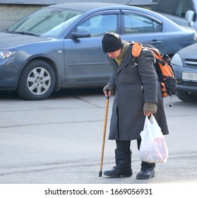 A Homeless Tramp With A Stick Walks Through The Parking Lot, Bolshevikov Avenue, Saint Petersburg, Russia, March 2020