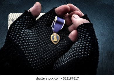 Homeless Veterans And Social Issues Concept With Grunge Image Of Dirty Hands Of A Homeless Man Wearing Fingerless Gloves And Holding A Purple Heart Medal