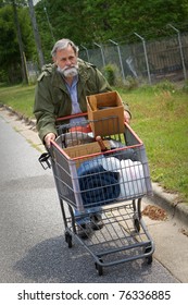 Homeless Vietnam veteran pushes a shopping cart containing his possessions down the side of the street.