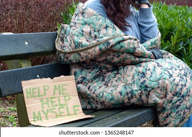 Homeless Woman On Park Bench With Cardboard Sign Reading Help Me Help Myself