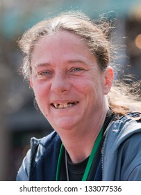 Homeless woman smiling with bad teeth. Outdoors during the daytime.